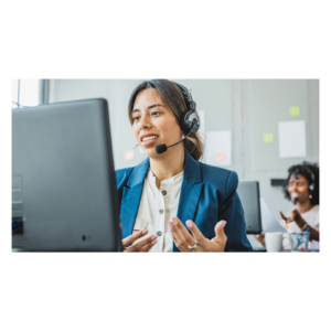 A person wearing a headset engaging in a video call at a desk, with another individual in the background, indicating a customer service or office environment.